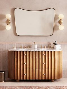 a bathroom vanity with two sinks and a large mirror above it, in front of a beige wall