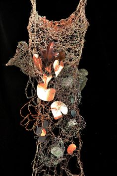 a piece of art made out of wire with shells and other things on it's sides