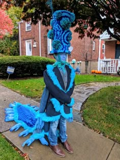 a man in a blue and black costume is standing on the sidewalk