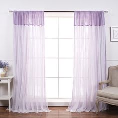 a white chair sitting next to a window covered in purple sheer curtaines and curtains