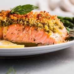 a piece of salmon on a plate with lemon wedges and parsley garnish