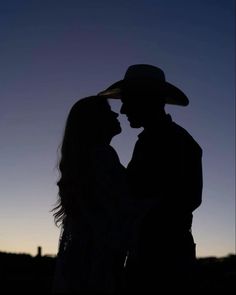 a couple standing next to each other in silhouette at sunset with the moon behind them