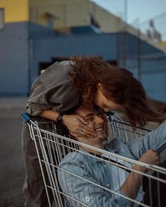 two people are sitting in a shopping cart and one is holding the other's head