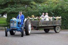 people are riding in the back of a tractor pulled by an old - fashioned trailer