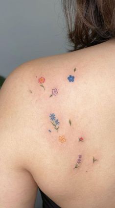 the back of a woman's shoulder with colorful flowers on her left arm and chest