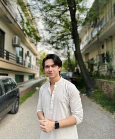 a man standing in the middle of a street next to a building with cars parked on it