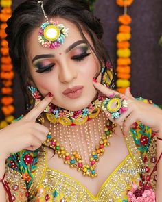 a woman in a yellow outfit with jewelry on her head and hands near her face