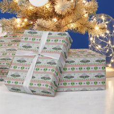 two wrapped presents under a christmas tree with lights on the top and below it is an ornament