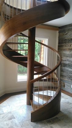 a spiral staircase in a home with stone flooring and wood railings on the sides