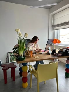 a woman sitting at a table working on her laptop in the middle of a room