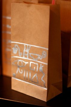 two brown bags with writing on them sitting on a table next to some drinks and straws