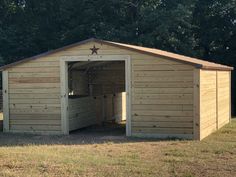 a large wooden shed with a star on the roof and side door open to reveal another room