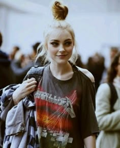 a woman with blonde hair wearing a gray shirt and blue jeans is walking down the street