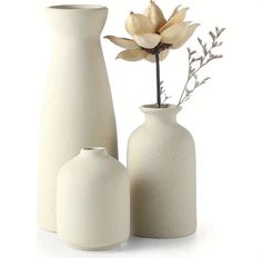 three white vases with flowers in them