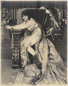 an old black and white photo of a woman sitting on a chair