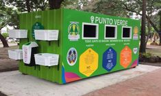 a green vending machine sitting on top of a cement slab next to a tree