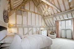 a bed sitting in a bedroom next to a window and a chandelier hanging from the ceiling