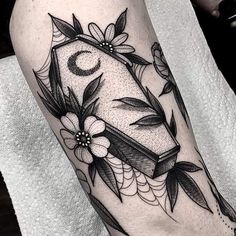 a black and white photo of a tattoo on the leg, with flowers around it