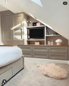 an attic bedroom with a bed, dressers and tv in the corner on the wall