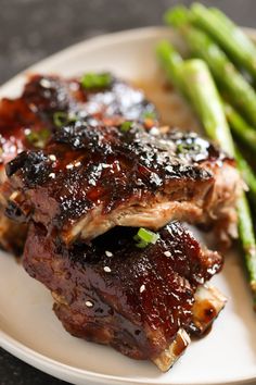 some meat and asparagus on a white plate