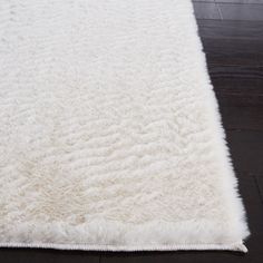 a large white rug on top of a wooden floor next to a black wood floor