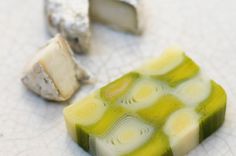 a piece of green and white soap sitting on top of a table next to two pieces of cheese