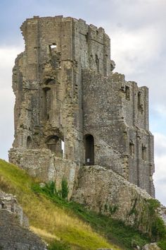 an old castle on top of a hill with grass growing up it's sides