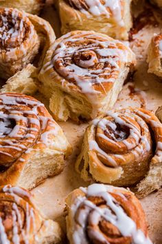 cinnamon rolls with icing sitting on top of a cutting board