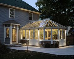 a house that is lit up at night with the sun shining on it's windows