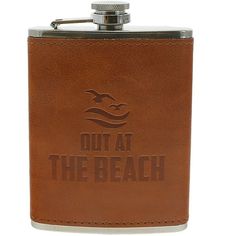 a brown leather flask with the words out at the beach on it's side