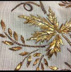 some gold leaves on a white cloth with beadings and beads in the middle