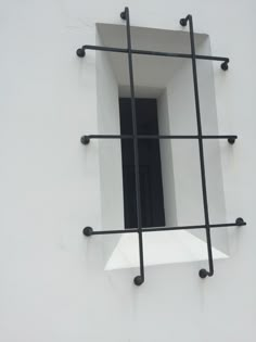 an open window on the side of a white building with bars in front of it