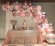 a table topped with lots of pink and white balloons