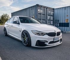 a white car parked in front of a shipping container