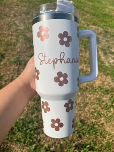 a hand holding a white coffee cup with brown flowers and the words steppanu on it