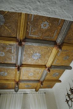 the ceiling is painted gold and white with intricate designs on it's sides, along with drapes