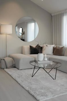 a living room with a white couch and round mirror on the wall next to it