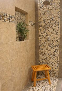 a small wooden stool sitting in the middle of a walk in shower next to a stone wall