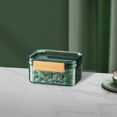 a glass container filled with green beans sitting on top of a counter next to a plate