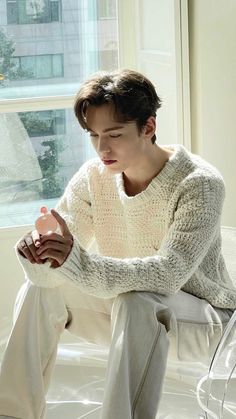 a person sitting on a bed with a white sweater