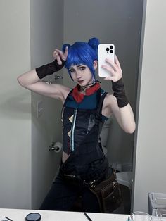 a woman with blue hair taking a selfie in front of a mirror while holding a cell phone