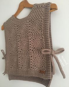 a crocheted sweater hanging on a wooden hanger