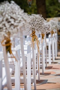 rows of white chairs with baby's breath flowers tied to the back and sides