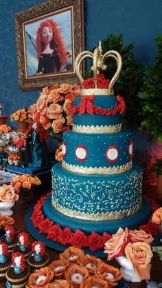 there is a blue cake with red flowers on the table