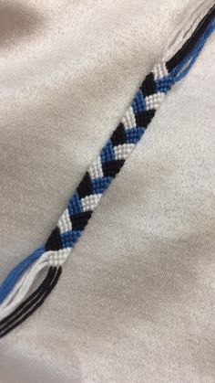 a blue and white braided tie laying on top of a white t - shirt