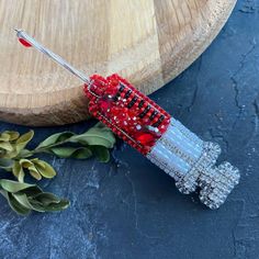 a red beaded object sitting on top of a wooden table next to a plant