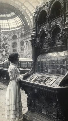 an old photo of a woman standing in front of a large machine that is on display