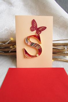 the letter s is made out of paper and sits on top of a red envelope