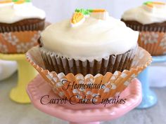 three cupcakes with white frosting sitting on top of a pink cake plate