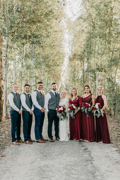 a group of people standing next to each other in front of trees and leaves on the ground